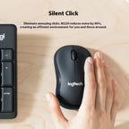 Logitech M220 silent click mouse on a wooden surface with a hand using it, next to a keyboard.