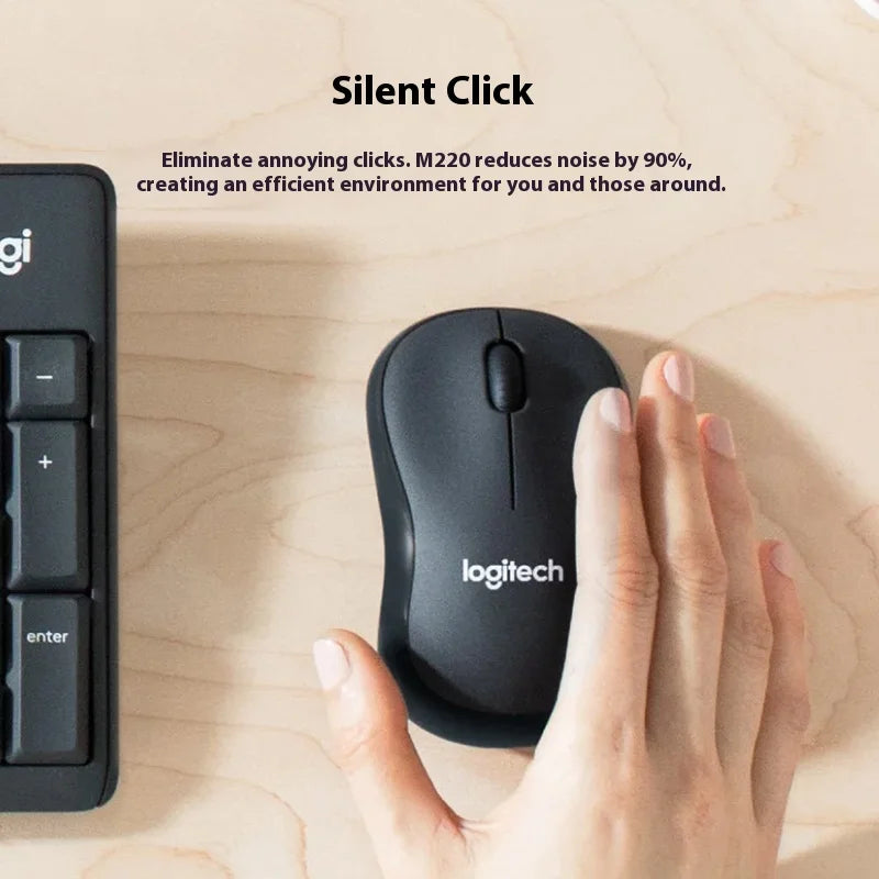 Logitech M220 silent click mouse on a wooden surface with a hand using it, next to a keyboard.