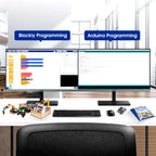 Two computer monitors displaying Blockly Programming and Arduino Programming on a desk with educational materials.