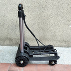 Black and silver hand truck on a tiled floor with a neutral wall background
